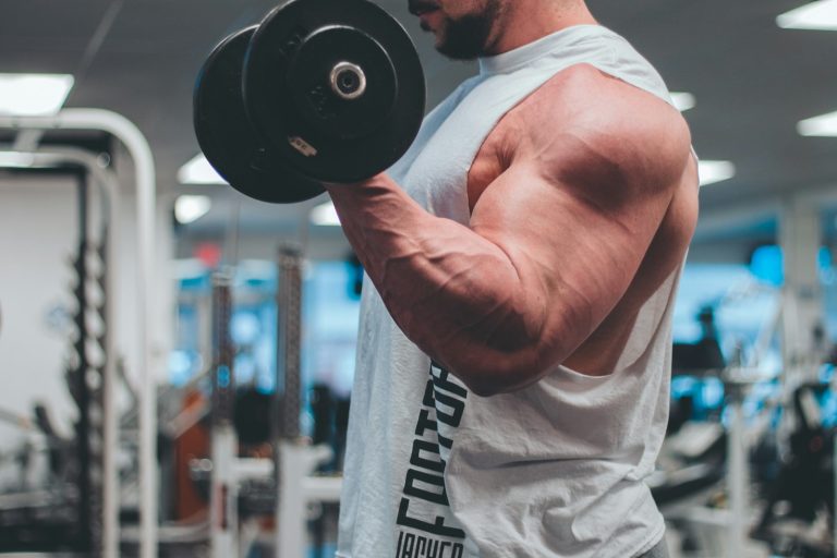 Anavar vs Testosterone man in white tank top lifting black dumbbell